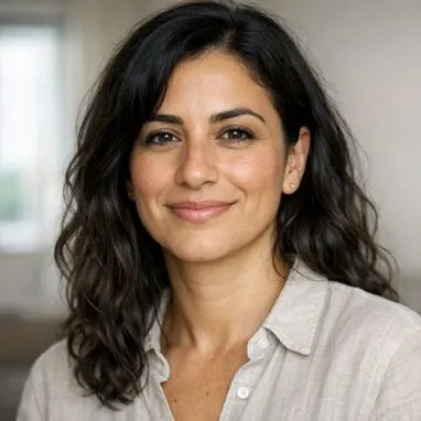 Woman in her late 30s, wavy dark hair, olive skin, calm expression